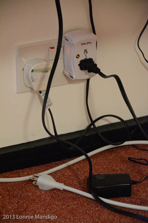 My one busy plug converter, camera battery charger plugged in.  Power cords for MacBook and USB battery on the floor.  The other cord plugged into the wall is for the lamp above the desk.